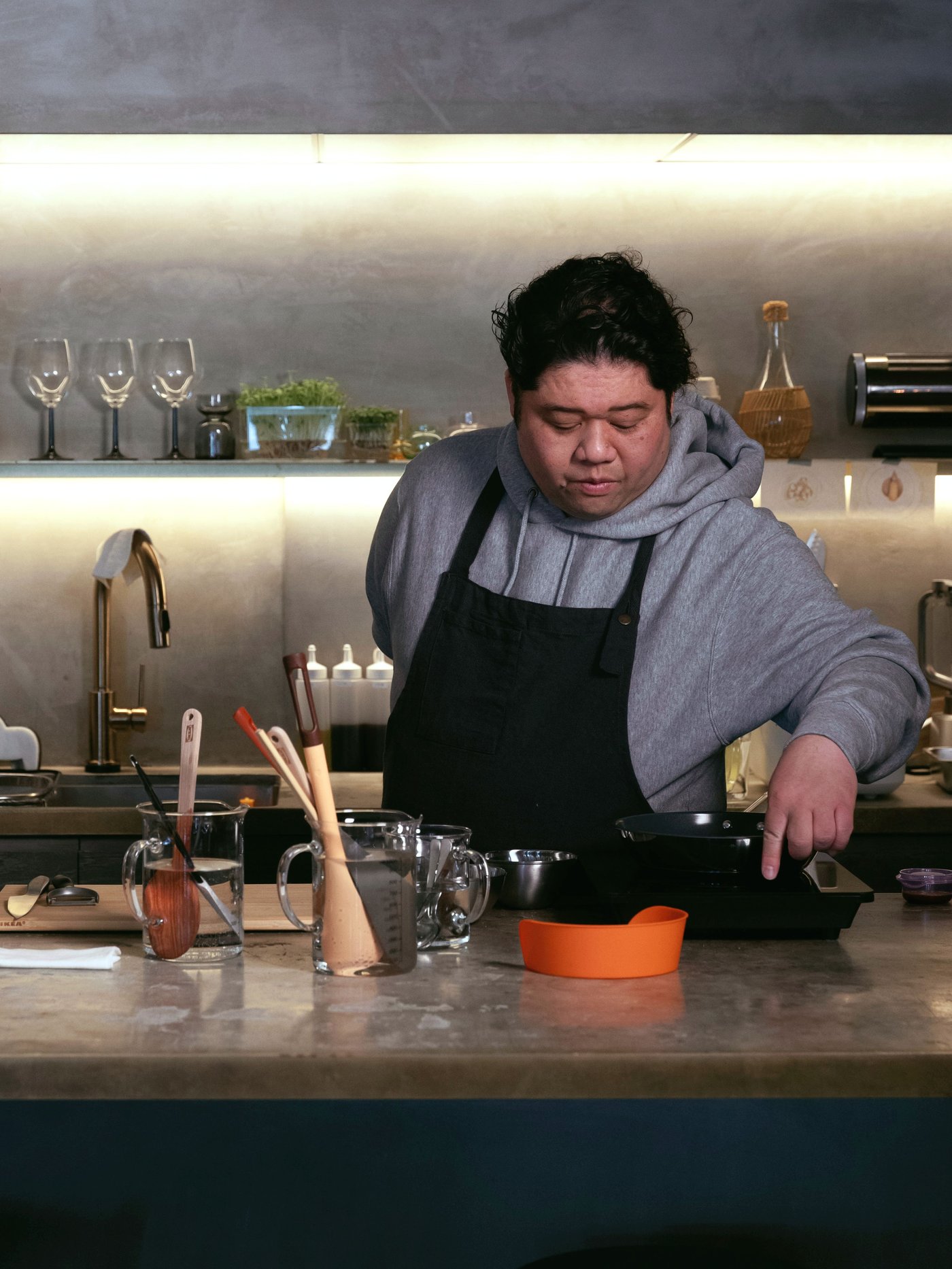 カウンターで飲み物を準備するシェフと、背後に並ぶボトルやグラスが見えるバーコーナー