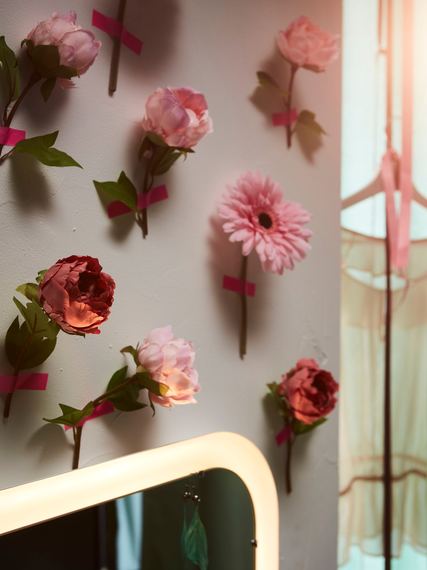 Eine Wand mit SMYCKA Kunstblumen Pfingstrose/rosa, die mit rosafarbenem Klebeband einzeln befestigt wurden.