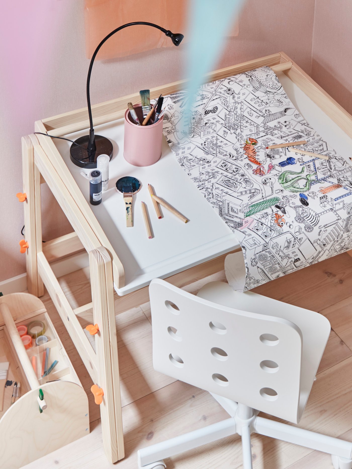 Una mesa infantil FLISAT de madera con lápices de color y una hoja para colorear.