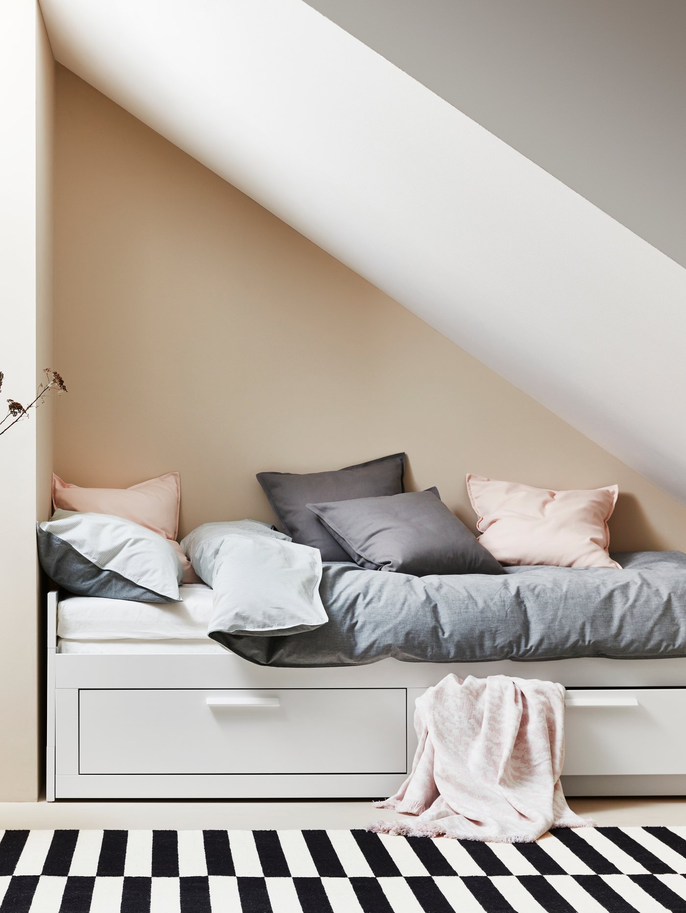 A lot of cushions in blue SISSIL cushion covers lie on top of two footstools against a wall in a run-down building.