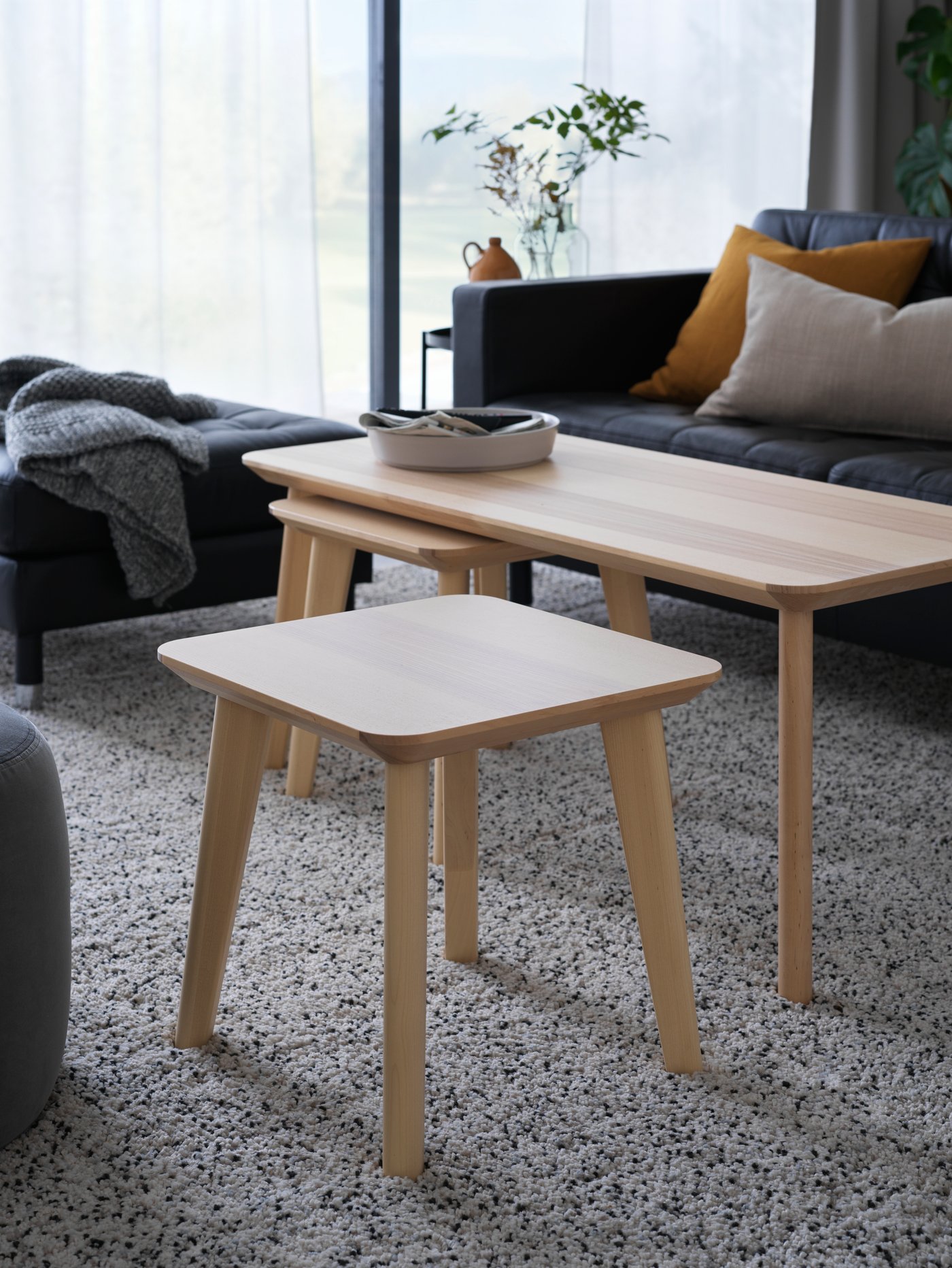 Deux tables d’appoint LISABO et une table basse LISABO, toutes trois revêtues d’un placage en frêne, devant un canapé MORABO dans un salon.