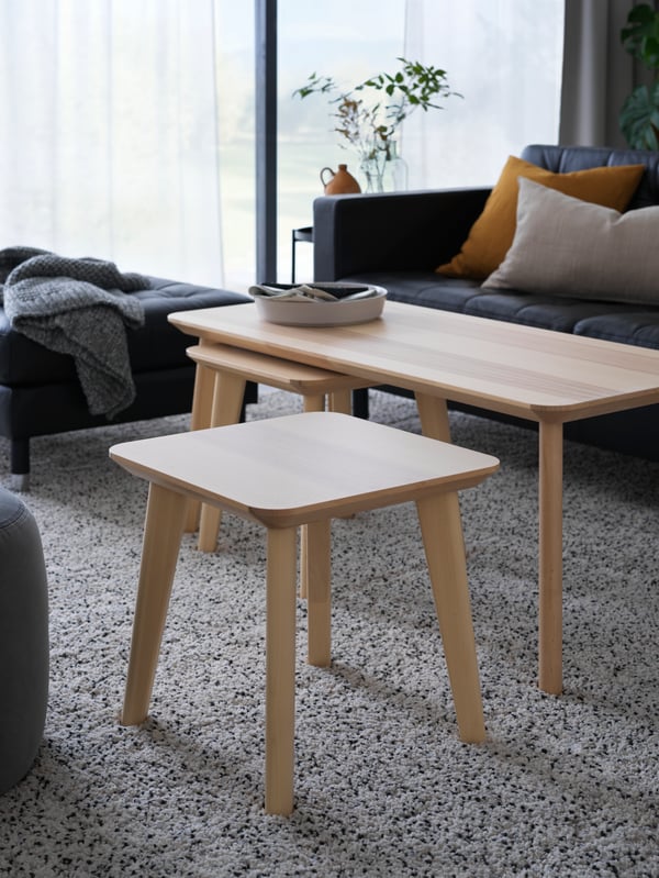 Two LISABO side tables and a LISABO coffee table, all made with ash veneer, in front of a MORABO sofa in a living room.