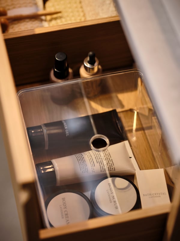 En åben skuffe med gennemsigtige kasser fyldt med makeup.