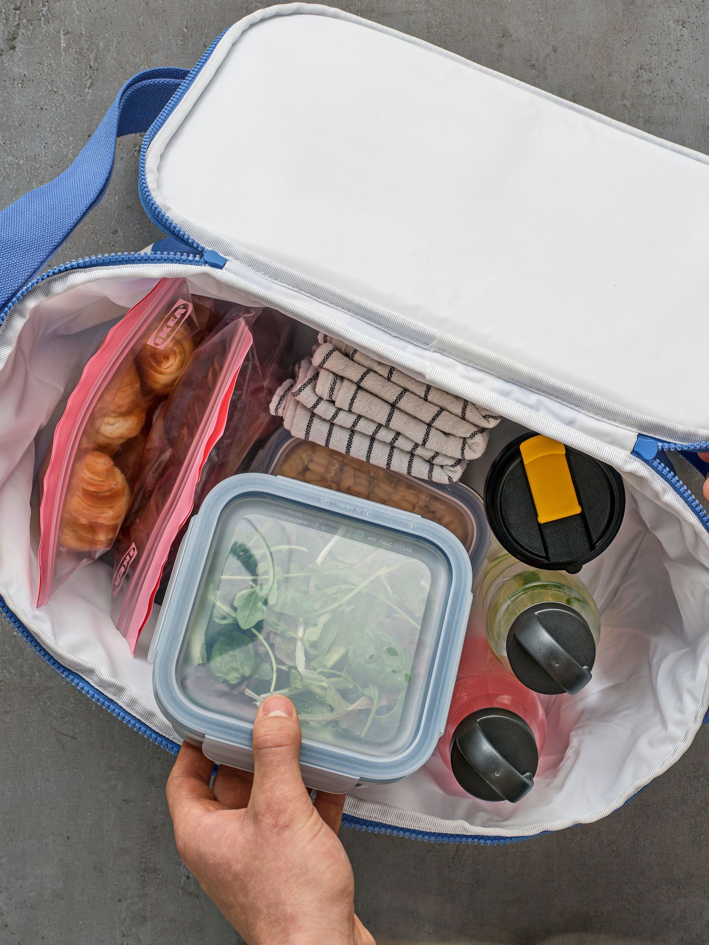 A square/plastic IKEA 365+ food container with lid in a lunch bag