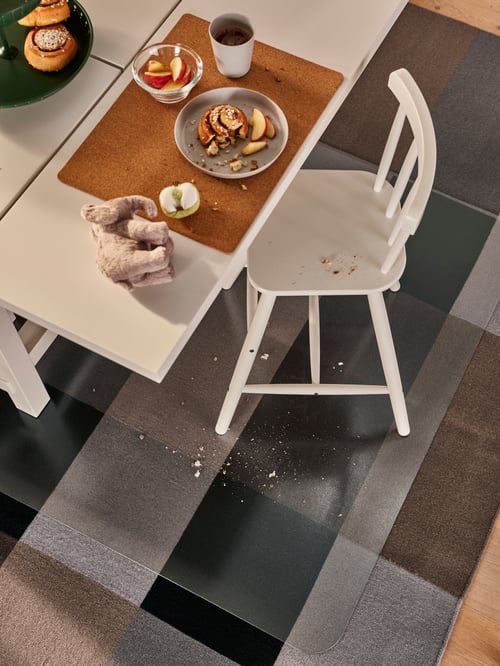 Dining room with a white transparent floor protector made of plastic, placed on top of a rug flatwoven and under a table.