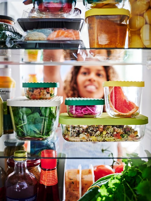 HAVSTOBIS recipiente alimentare pline cu alimente, așezate pe rafturi de sticlă și o persoană care se uită prin ele.