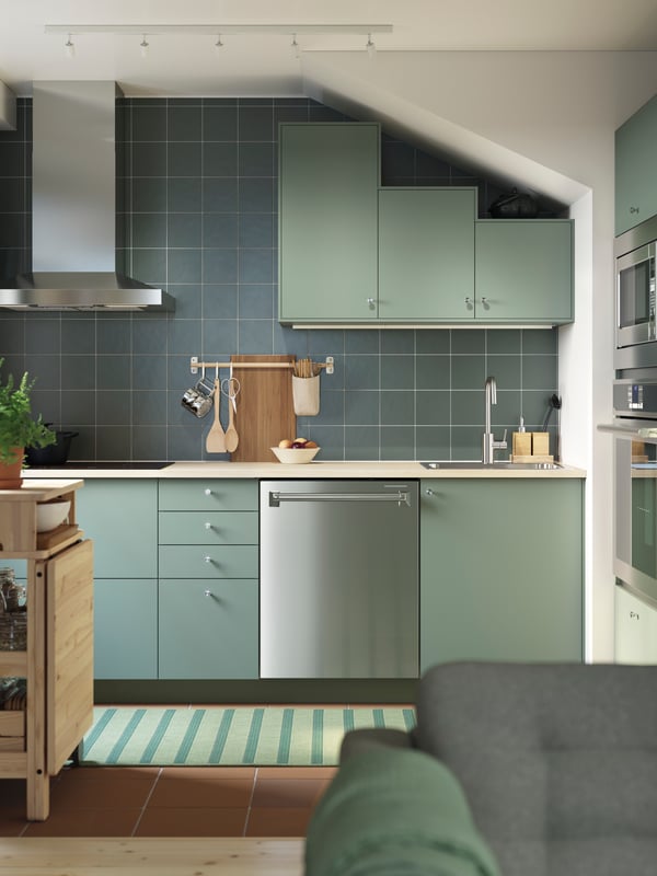 A gray green NICKEBO kitchen has base cabinets and wall cabinets under a slanted ceiling and a RESARÖ mobile drop-leaf table.