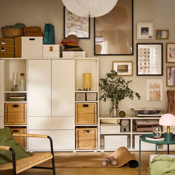 A living-room wall half-covered by a white VIHALS storage combination, the other half covered by a cluster of framed art.