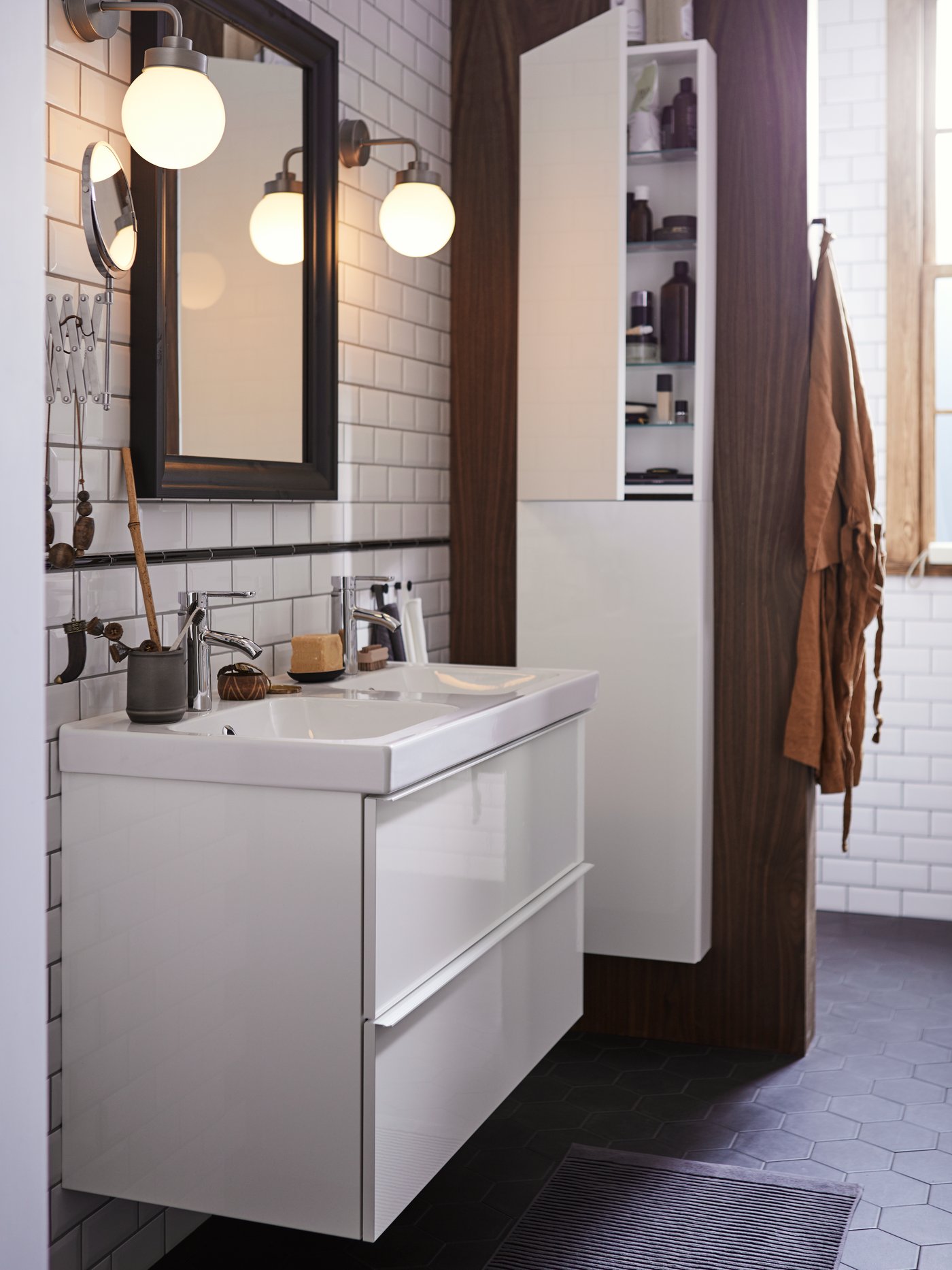A GODMORGON bathroom with a two drawer wash-stand with a mirror above and an ajar high cabinet to the right, with toiletries.