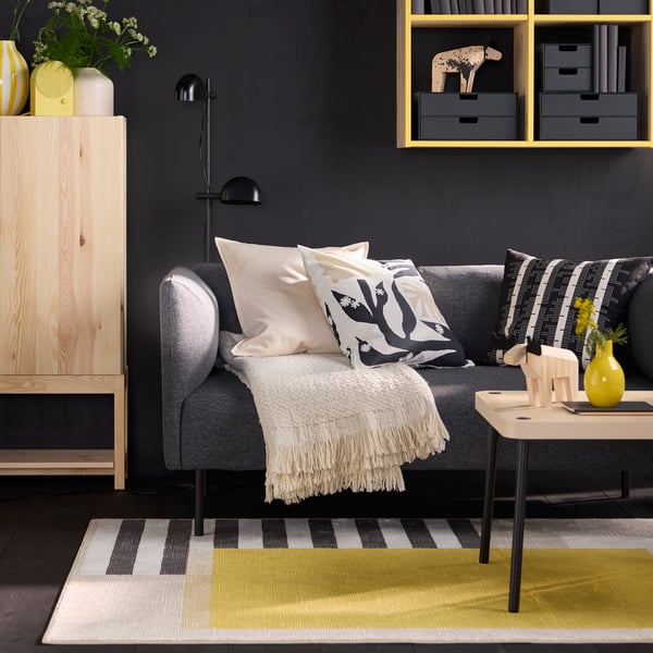 A moose decoration sits on a table placed on a multicolour ELSYSTEM low pile rug by a grey sofa with an off-white throw.