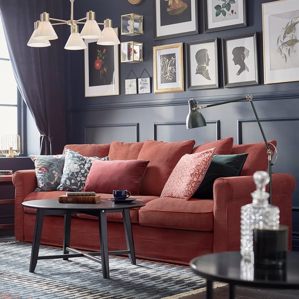 Eleganter Wohnraum mit rotem Sofa, dunkler Wand, stilvoller Bildergalerie und schwarzem Couchtisch mit Tassen und Deko