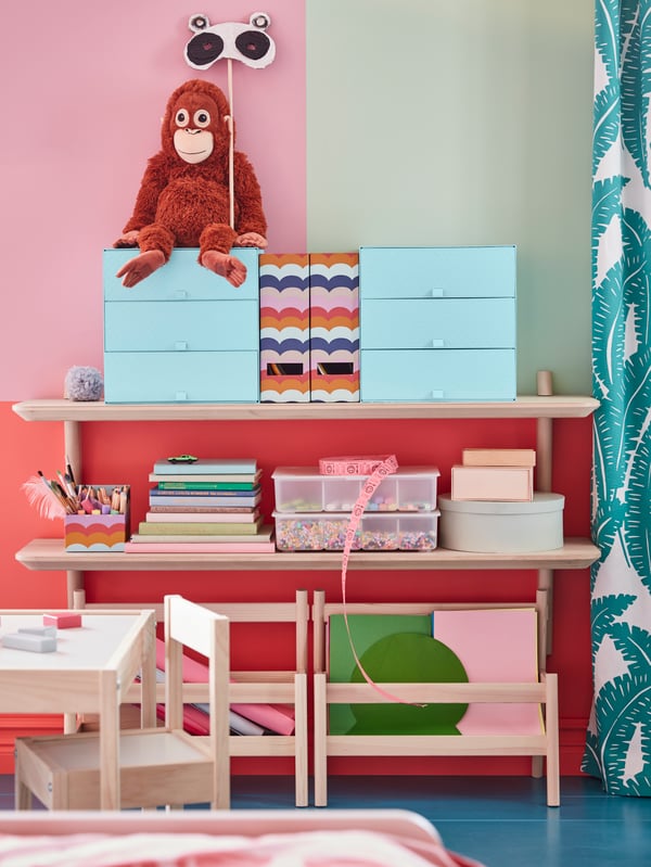 Two light blue PALLRA mini chests with 3 drawers, a monkey soft toy, books and boxes sit on two LISABO wall shelves.
