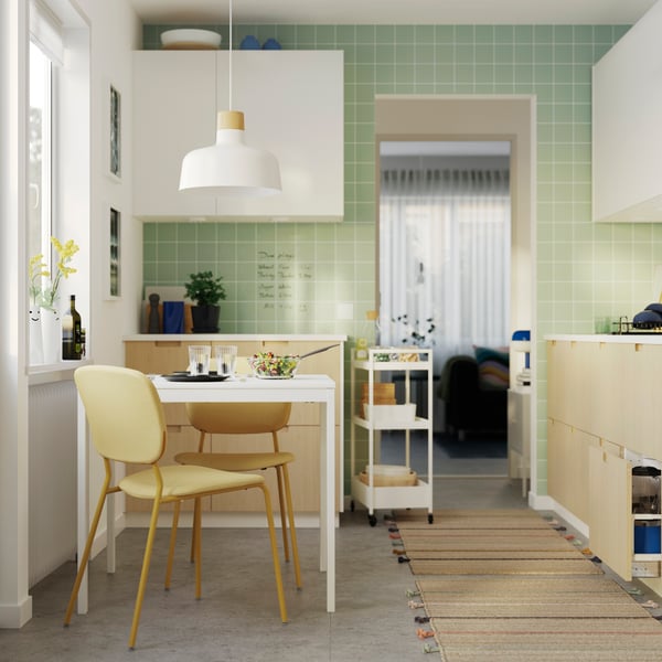 A small kitchen has several base and wall cabinets with grey-green ASPUDDEN fronts and an extractor hood next to a window.