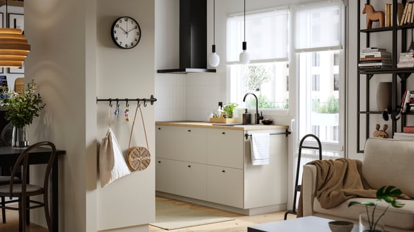 A kitchen with a window and a balcony door has beige HAVSTORP fronts and a MATÄLSKARE wall mounted extractor hood in black.