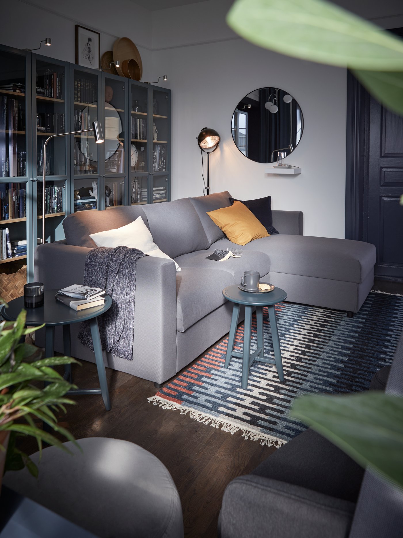 A dark grey corner sofa in the living room next to a black SVARTNORA floor lamp.