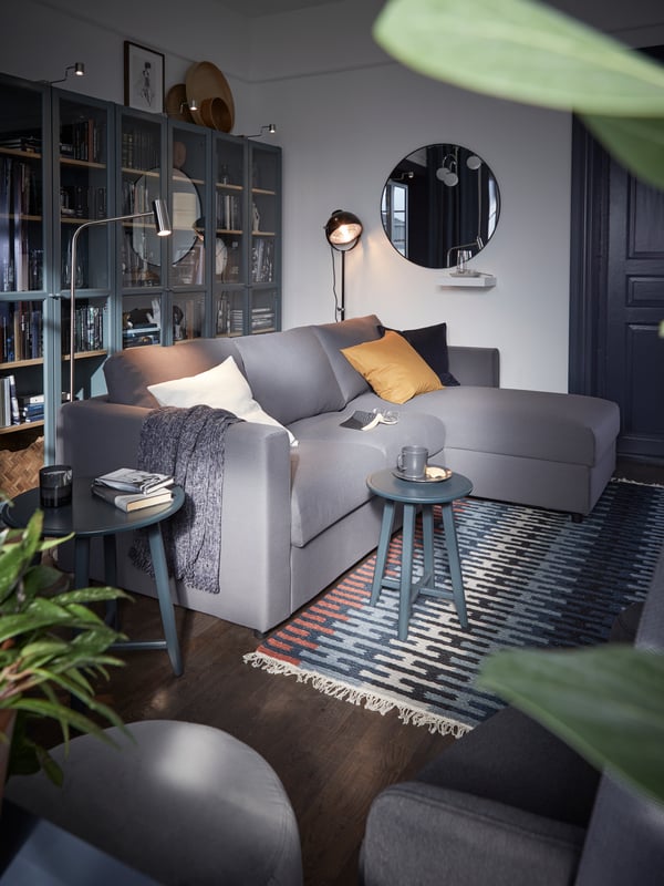 VIMLE L-shaped 3-seat sofa in Hallarp grey covers with a row of wall shelves behind in a traditional design room.