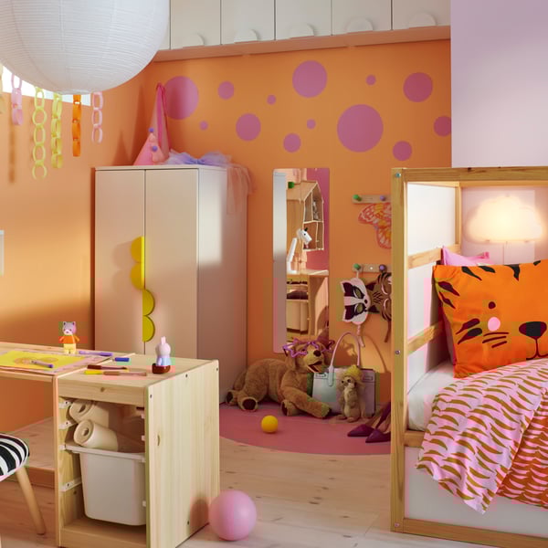 A light white stained pine TROFAST frame and tabletop combined into a desk in a child’s room in front of a SMÅSTAD wardrobe.