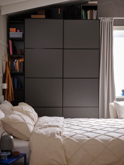 Bedroom featuring a grey PAX wardrobe combination placed next to a grey MAJGULL pair of room darkening curtains.