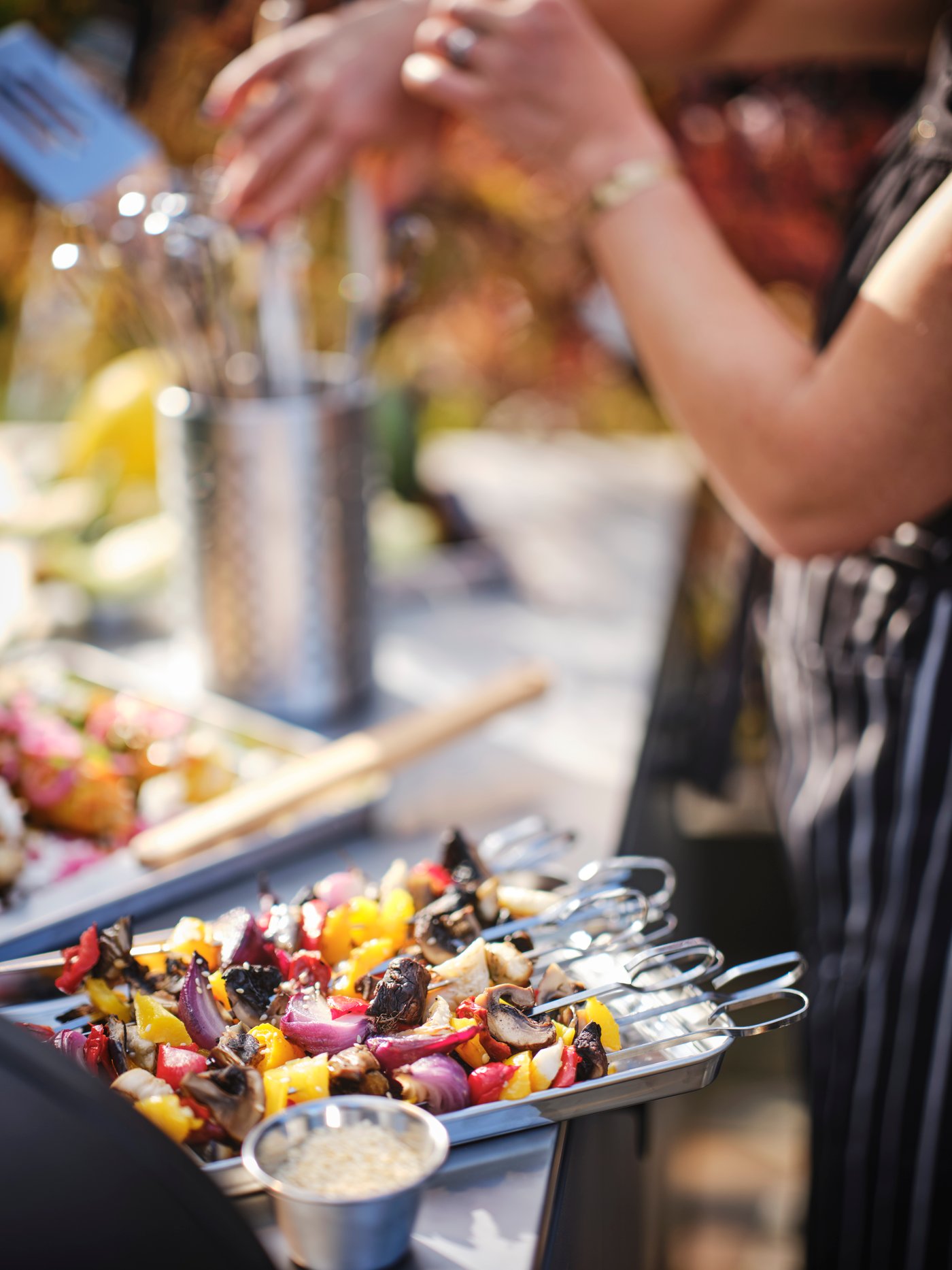 Detalle de brochetas de verduras sobre una bandeja de acero inoxidable.