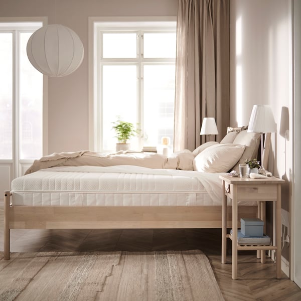 ÅNNELAND foam and spring mattress on bed frame in room with bedside table.