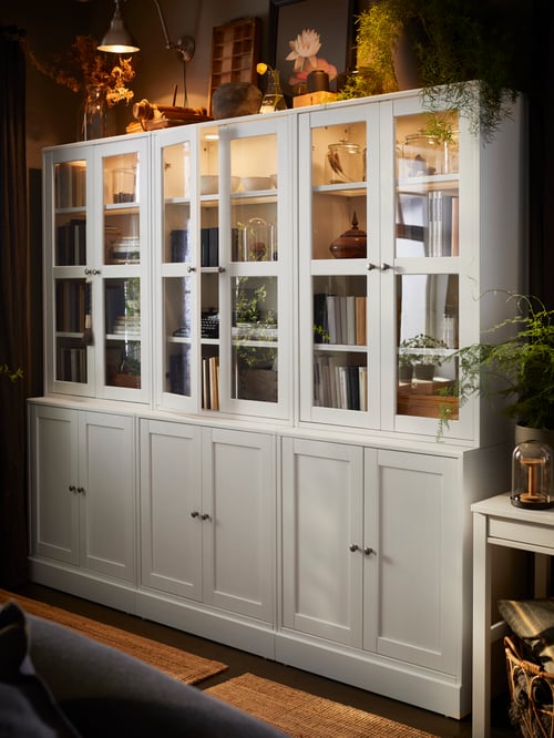 Living room area featuring multiple storage combinations with glass doors, and a white desk next to them.