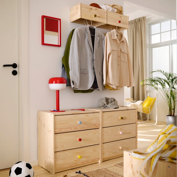 Hallway with RAST chest of drawers in pine and RAGGBERG coat racks with shelf on the wall above. A bright red lamp and mirror.
