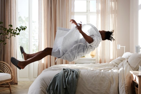 A boy in pyjamas jumping on a bed