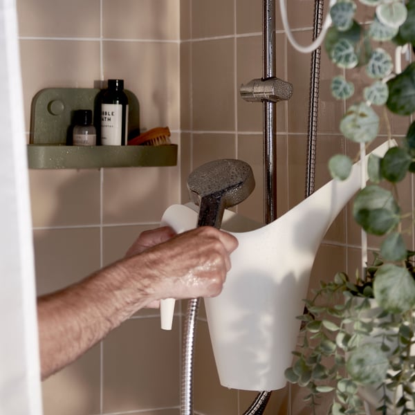 A white IKEA PS 2002 watering can in the bathroom