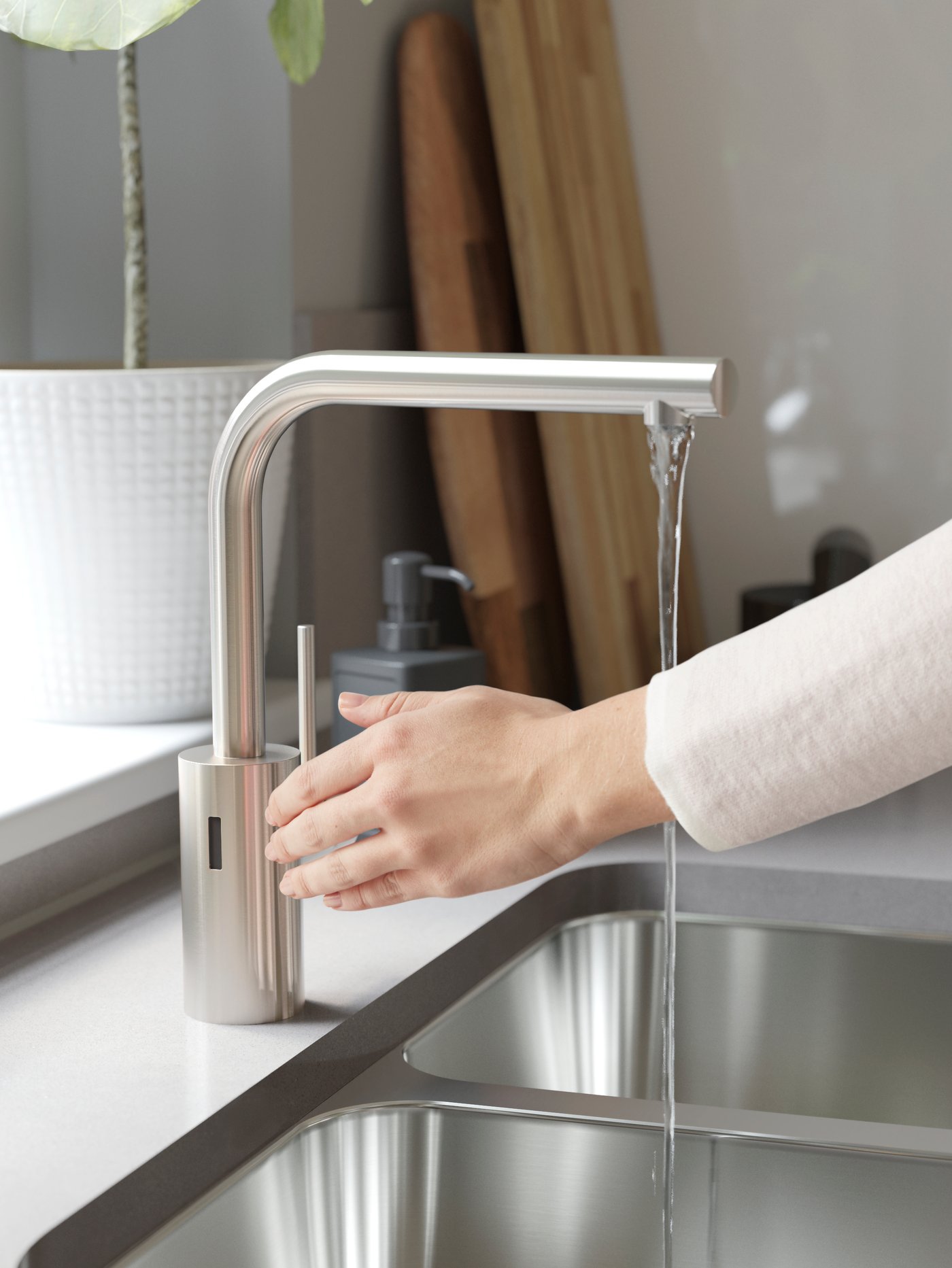 Eine Hand aktiviert mit einer Geste den Sensor einer Küchenmischbatterie.