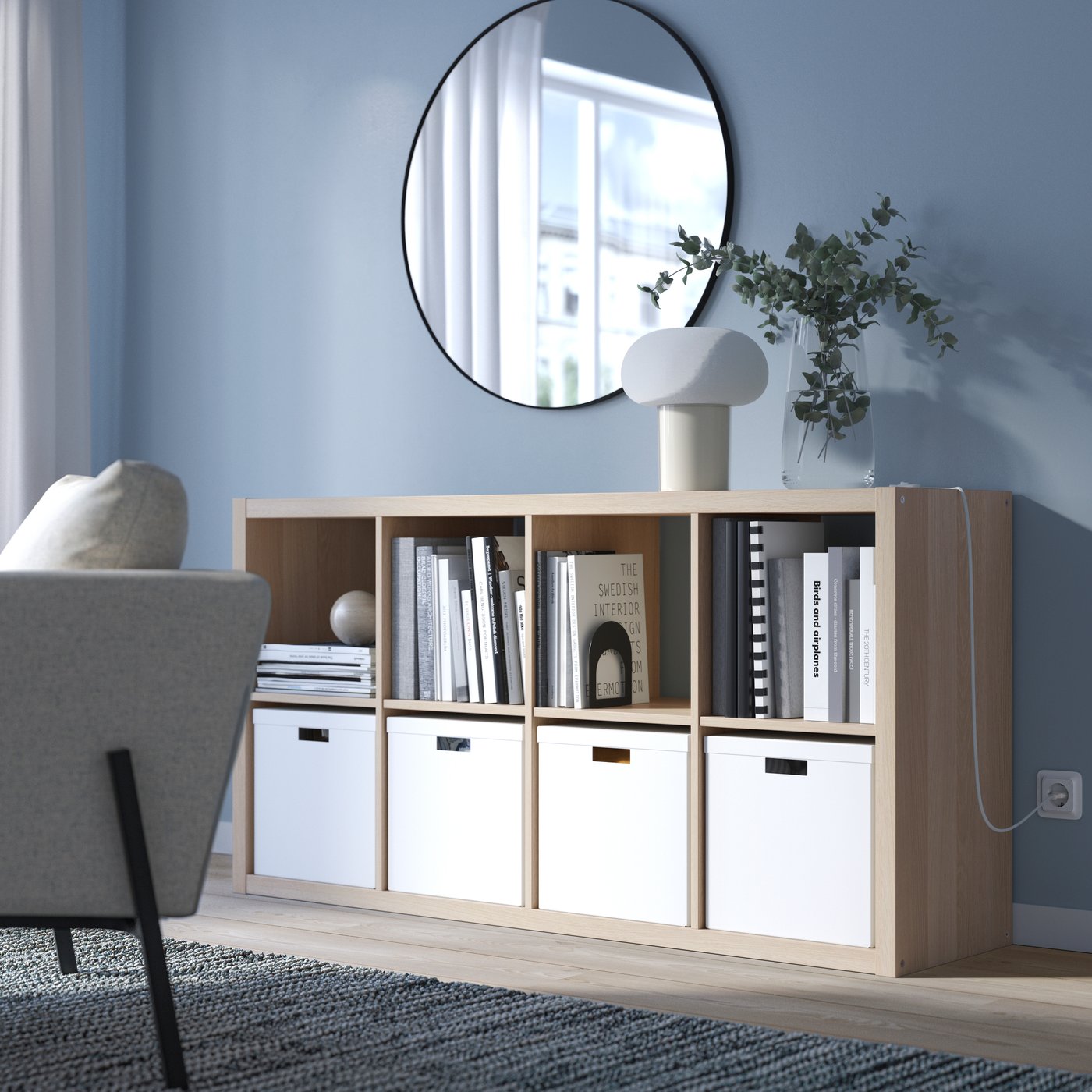 Una sala con un estante KALLAX color madera usado para organizar libros y decoraciones.
