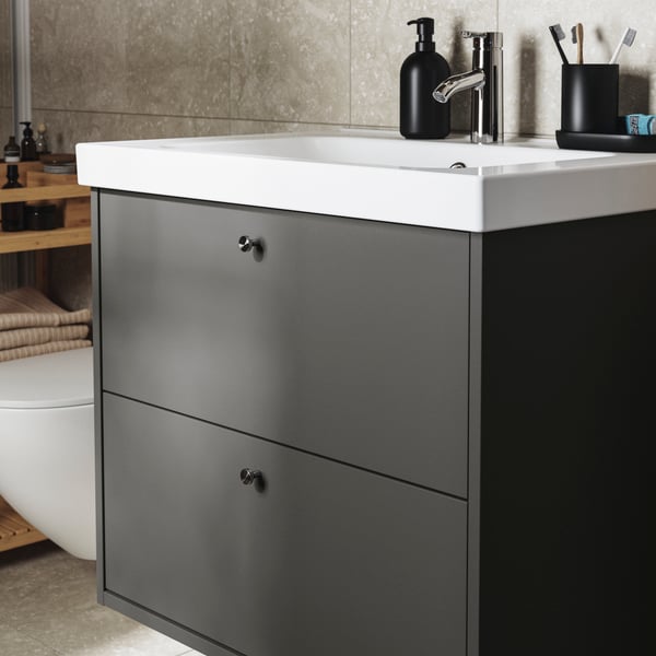 A dark-gray HAVBÄCK vanity with two large drawers and an ORRSJÖN white sink. A toothbrush holder in stoneware.