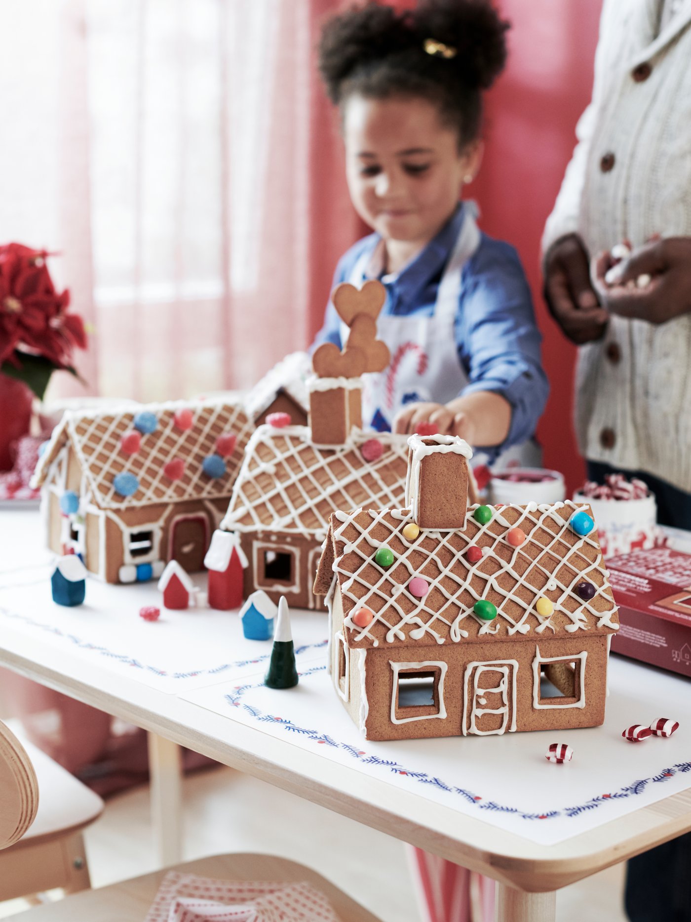 Et barn pynter pepperkakehuset.