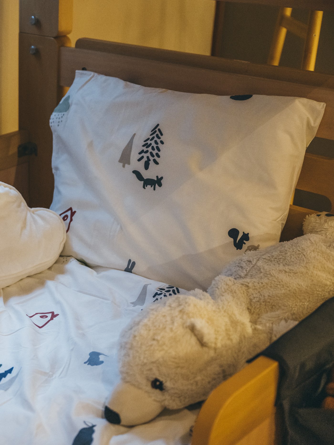 バーンドローム掛け布団カバー、枕カバーがかかったベッドに白クマのぬいぐるみが置いてある。