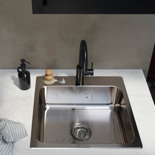 A stainless steel LÅNGUDDEN top-mount sink with a sleek black faucet, kitchen towel and soap dispenser on a white countertop.