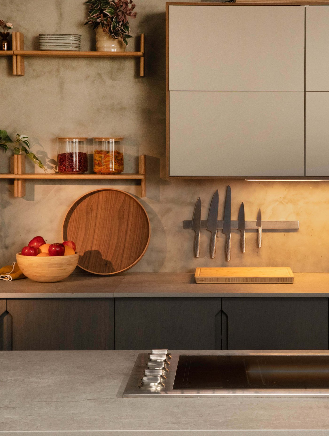 Modern kitchen with open shelves, cutting boards, knives, and a bowl of apples.