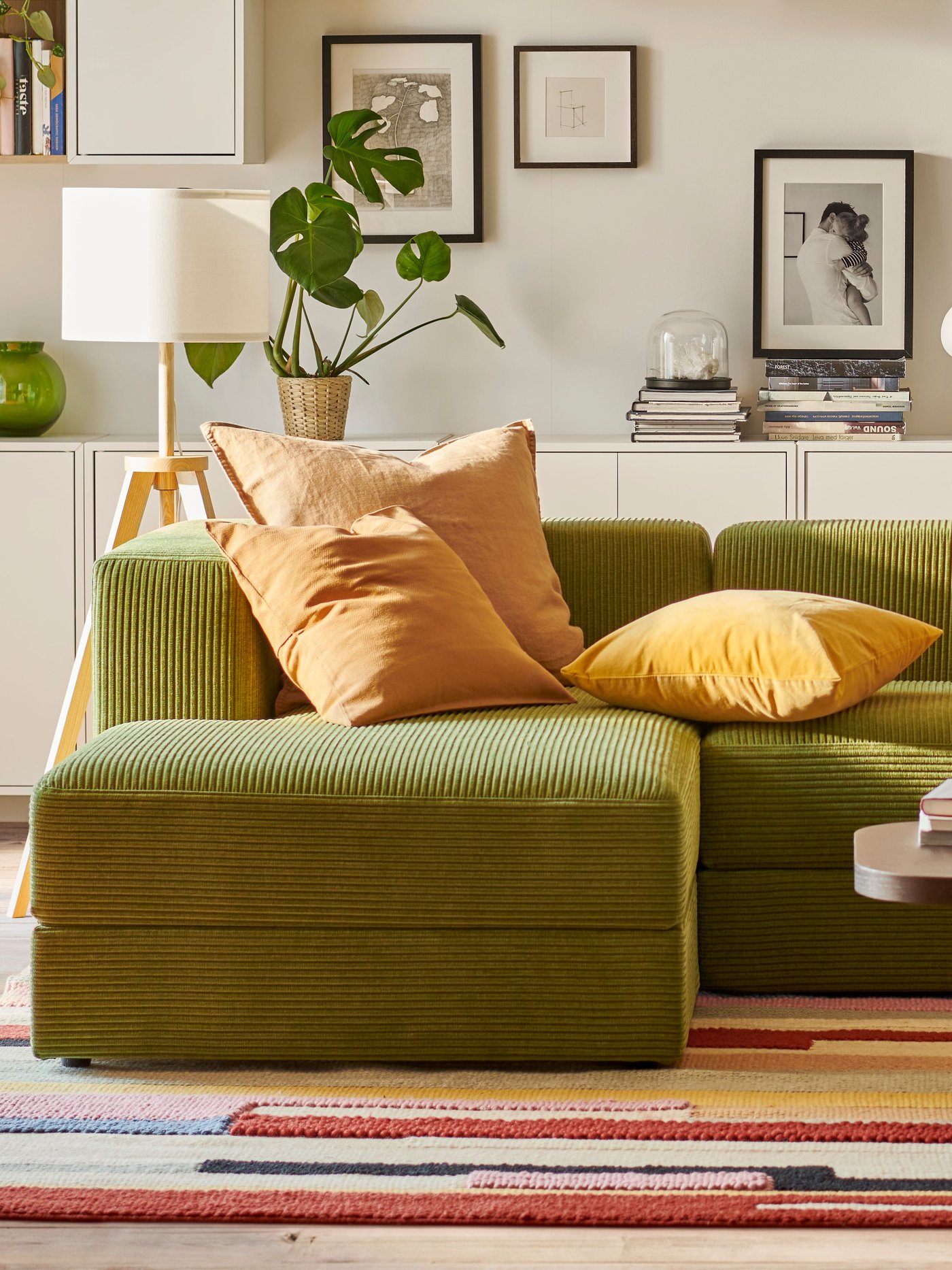 Een JÄTTEBO 3,5-zitsbank met chaise longues en EKET wandkasten staan in een woonkamer in mid-century moderne stijl.