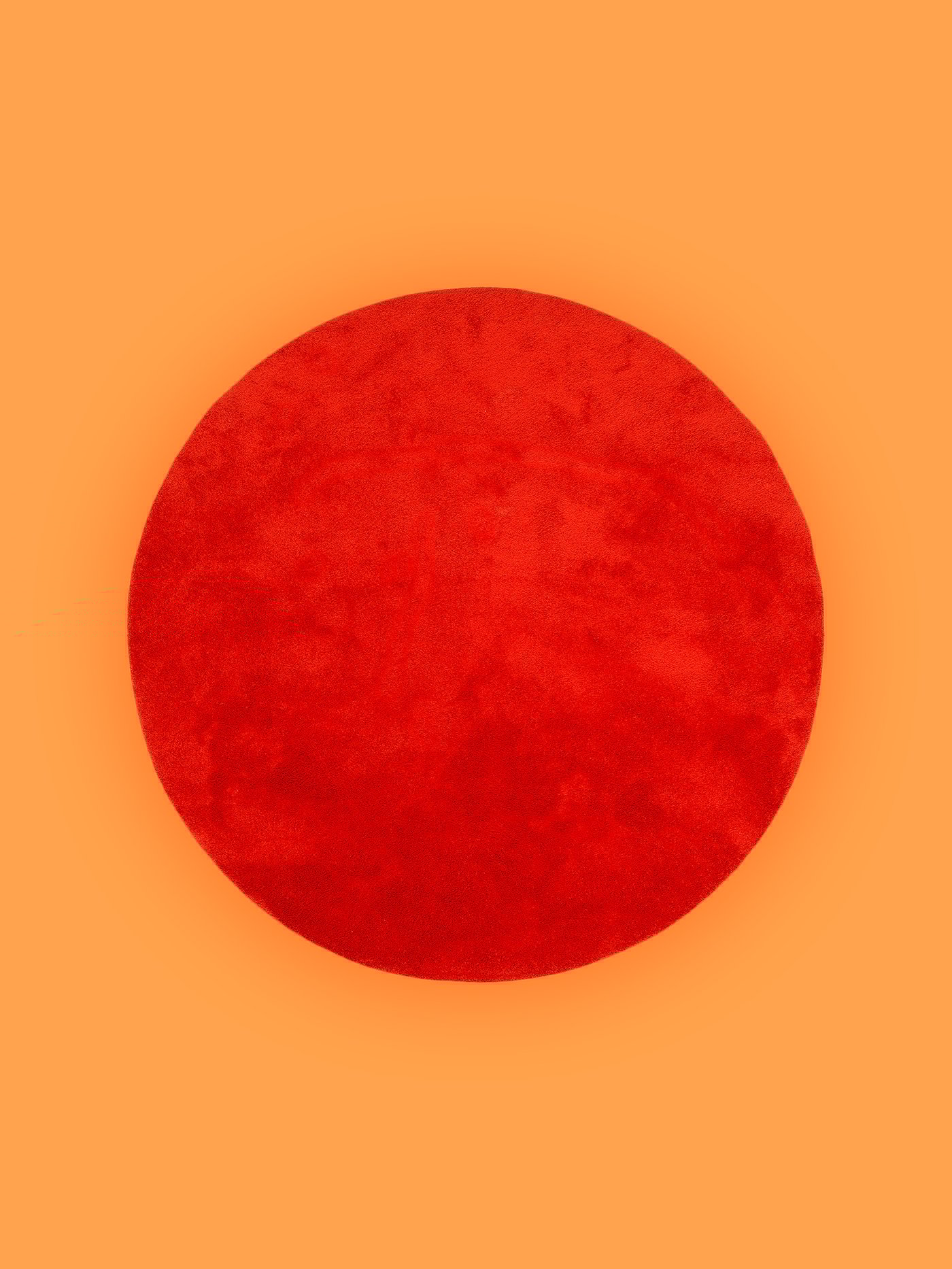 Okrogla rdeča preproga IKEA pred oranžnim ozadjem.