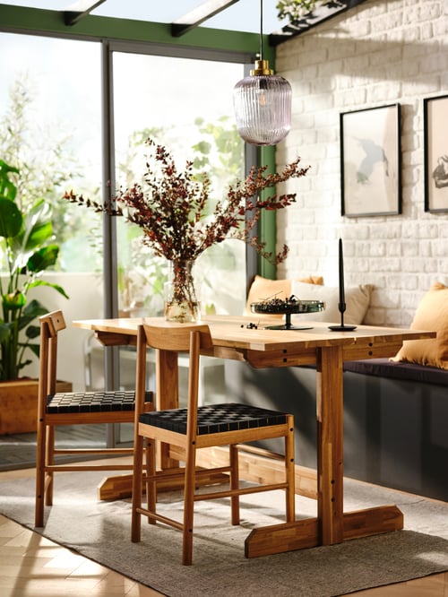 A modern dining room that features a rectangular table made from acacia wood that can seat four to six people.
