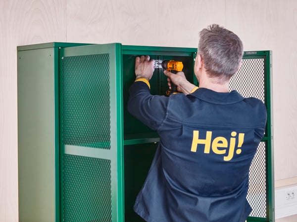 En medarbetare monterar ett grönt skåp.