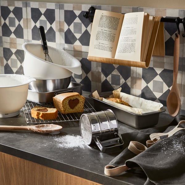 Przesiewaczka do mąki, miski i inne akcesoria do pieczenia na blacie kuchennym.