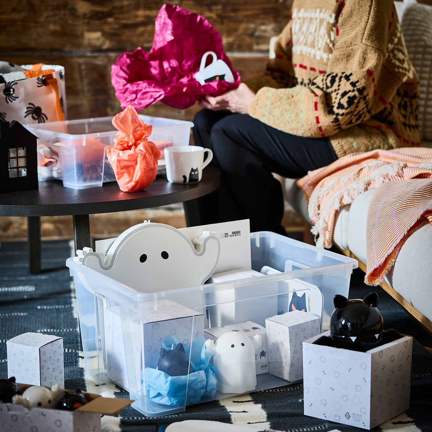 A large SAMLA storage box on the floor filled with Halloween-themed decorative items from the KUSTFYR collection.