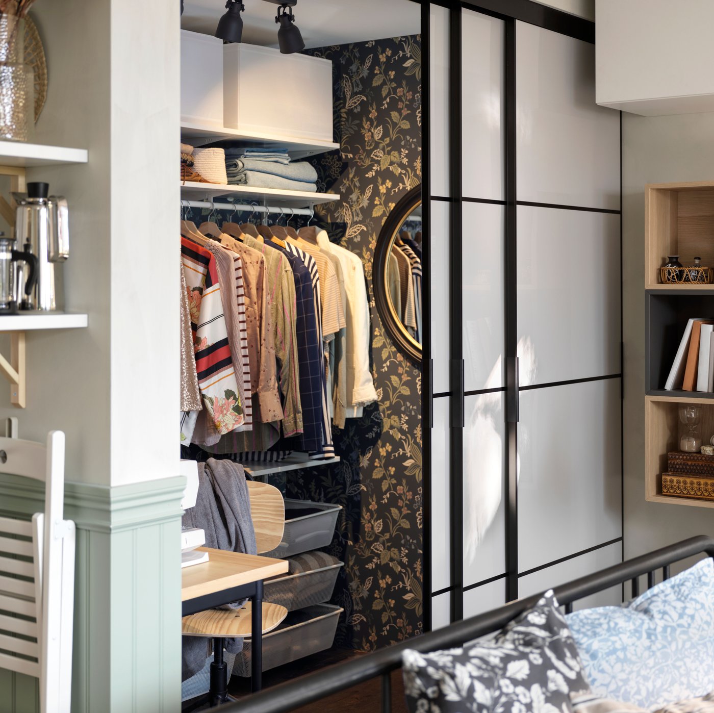 A black FYRESDAL day-bed in front of open SKYTTA/HOKKSUND sliding doors, revealing different types of clothes storage.