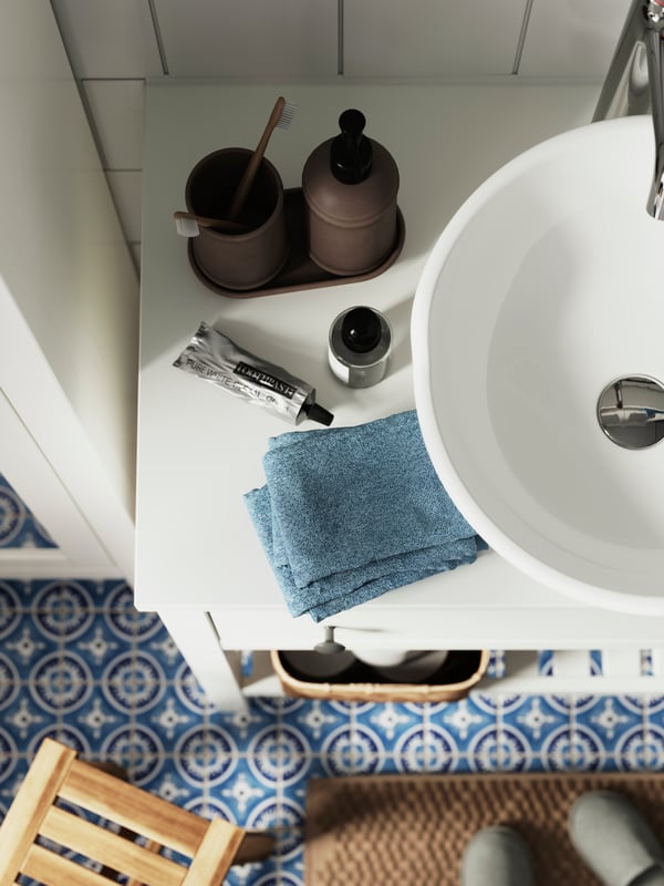 Joc de bany ÅLTJÄRN amb un porta-raspalls de dents i un dispensador de sabó sobre una safata a sobre d'un armari de lavabo HEMNES blanc.