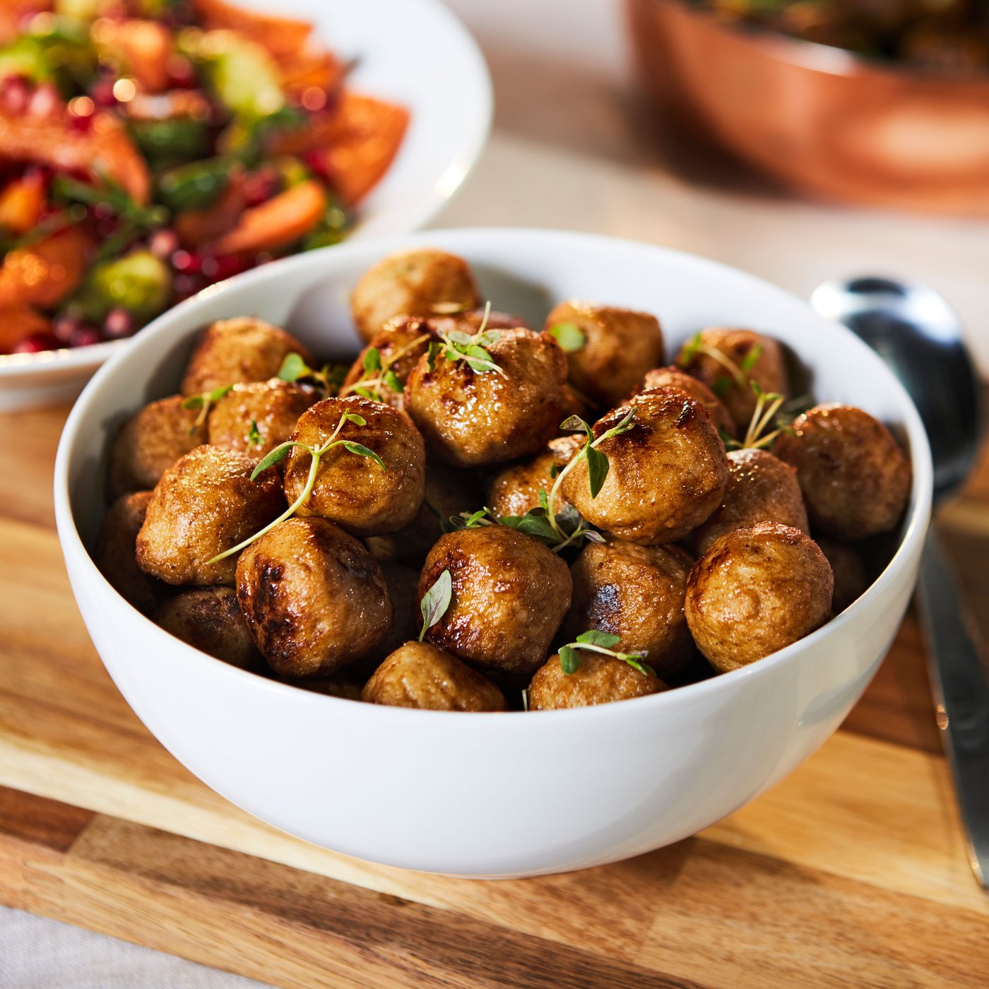 Valkoisessa IKEA 365+ -sarjan kulhossa kanapyöryköitä puisen leikkuulaudan päällä.