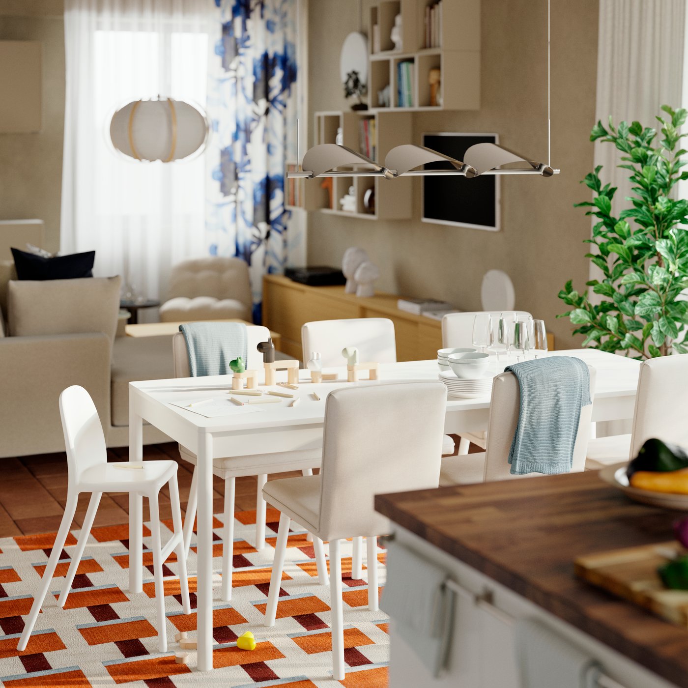 A TONSTAD extendable table with chairs is placed on a colourful rug in a dining room between a kitchen and living room.