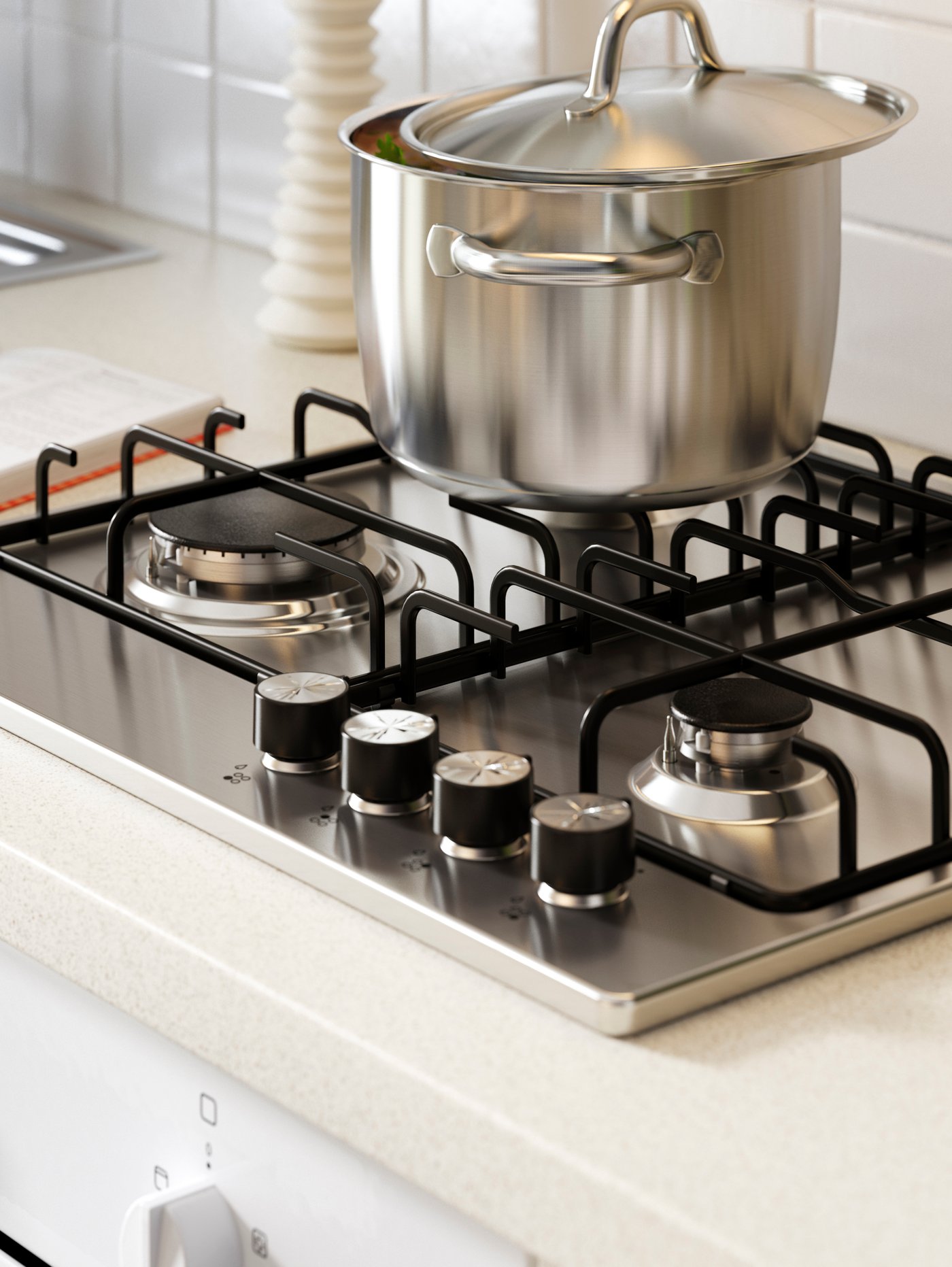 A silver pot on a hob in a kitchen with a white worktop next to a metal sink.