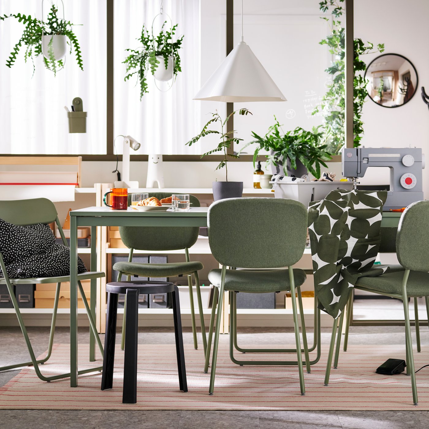 In einem multifunktionalen Esszimmer stehen VIHALS Stühle und ein Hocker an einem grünen VIHALS Ausziehtisch.