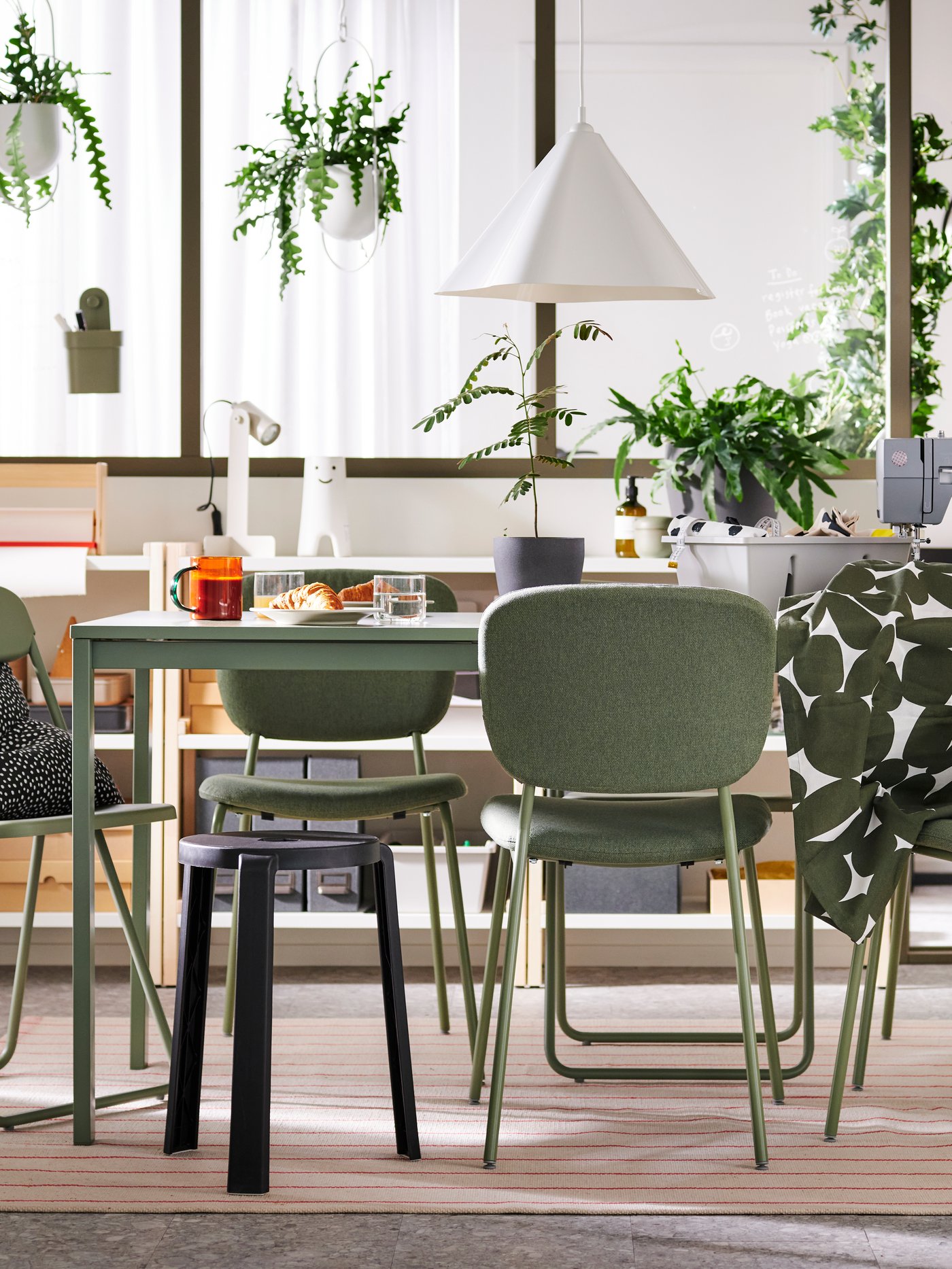 In einem multifunktionalen Esszimmer stehen VIHALS Stühle und ein Hocker an einem grünen VIHALS Ausziehtisch.