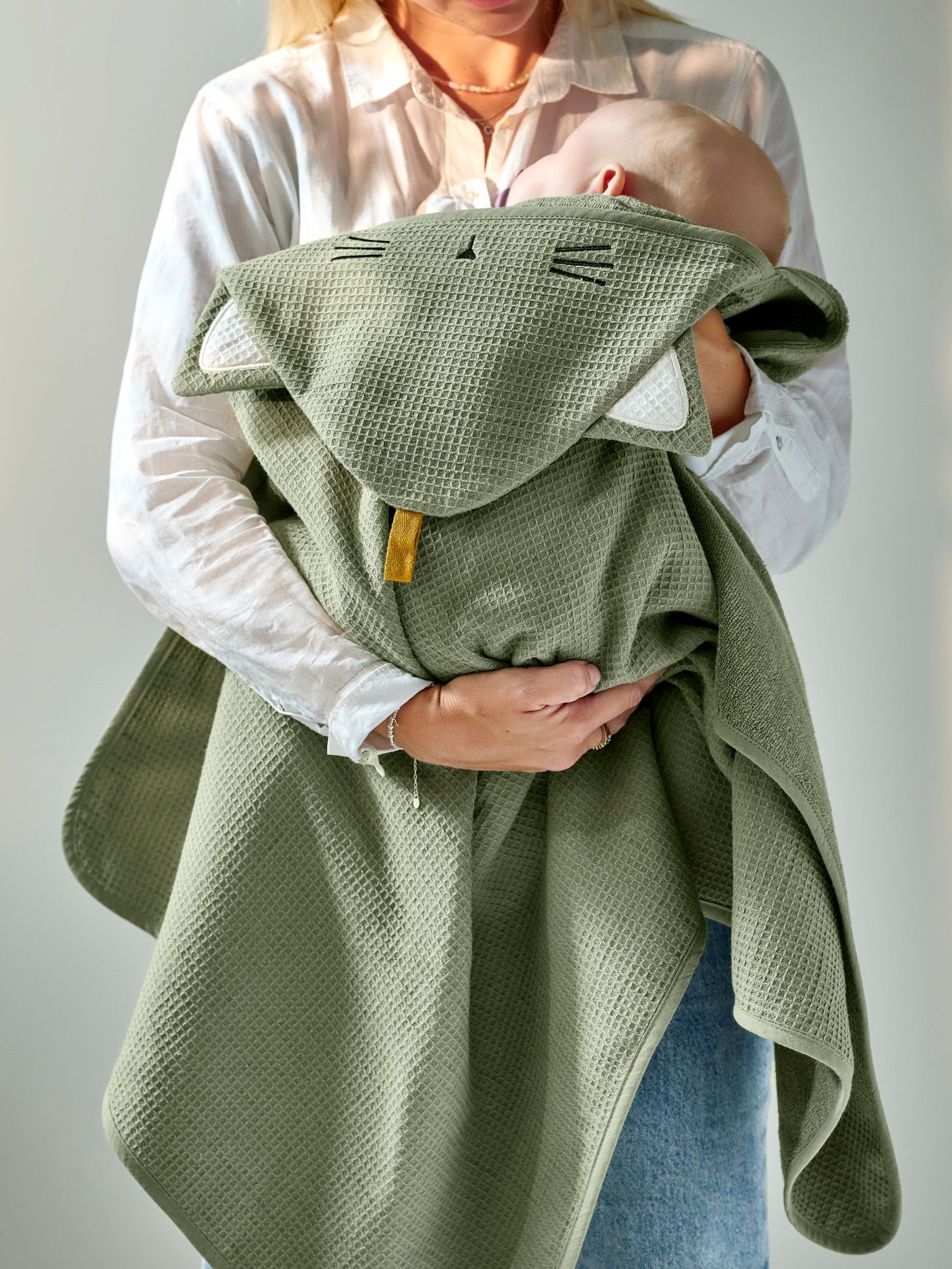 Una mujer sostiene a un bebé envuelto en una toalla GULDVÄVARE.