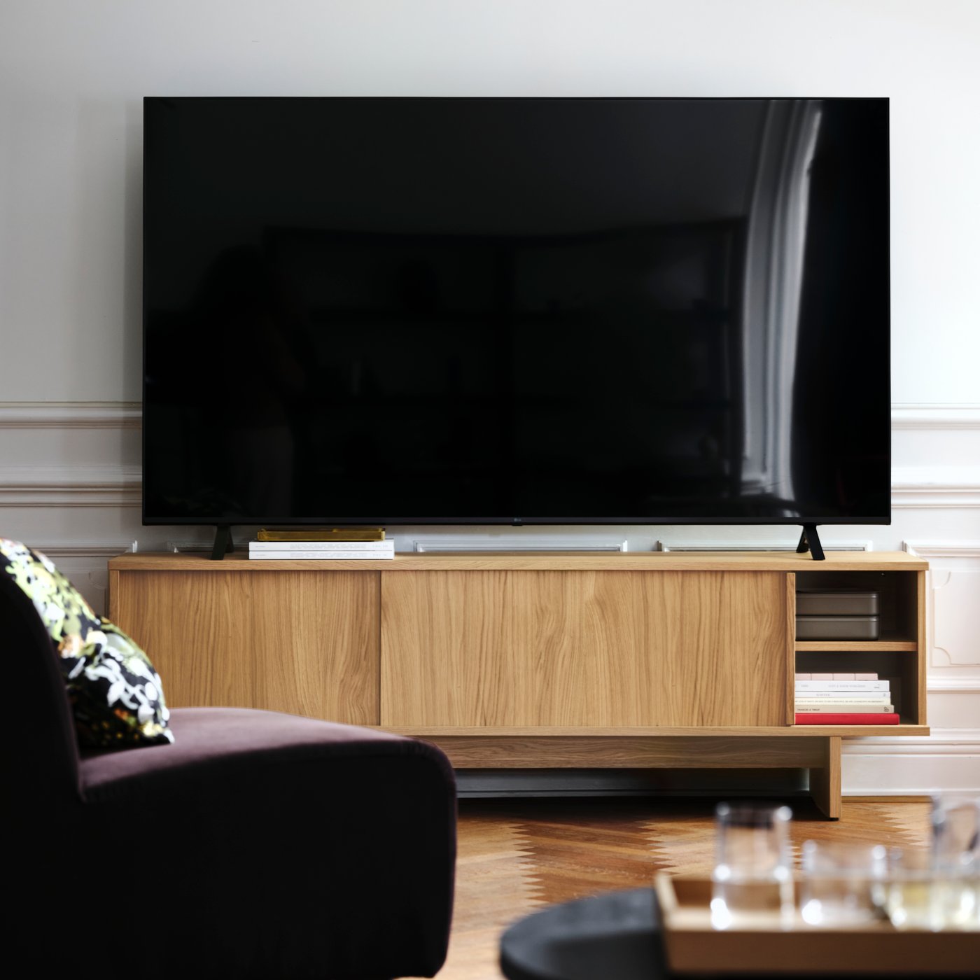 Tv-bänk i ek med skjudörrar i vardagsrum med tv-placerad ovanpå.